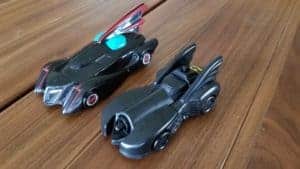 Two different Batman Batmobile toys on a wooden table